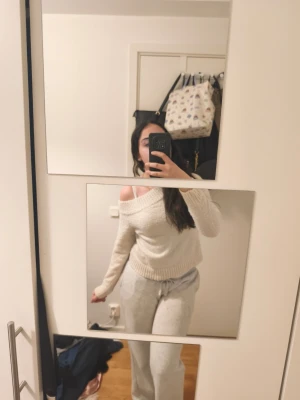 Beige off shoulder loungewear-set - Mysigt loungewear-set i beige med off shoulder-tröja och matchande byxor. Tröjan har bred ribbad mudd och avslappnad passform, medan byxorna har dragsko i midjan för extra komfort. Perfekt för chill dagar hemma.