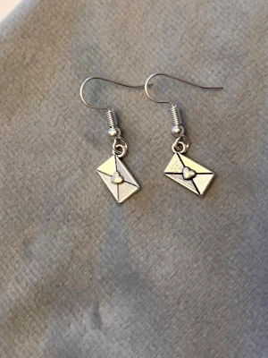 Love letter Örhängen Smycke Silver Imitation Brev  - Fina örhängen med berlocker av brev med hjärta på! Berlockerna är ca 1 x 0,5 cm. Silverimitation. 