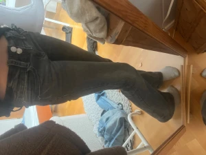 Svarta bootcut jeans med låg midja - Snygga svarta bootcut jeans med lågmidja och dubbla knappar framtill. Jeansen har klassiska fickor både fram och bak och är tillverkade i ett stretchigt denimtyg som sitter bekvämt. Perfekta för en trendig och avslappnad look.