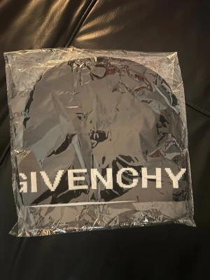 Svart mössa från Givenchy - Snygg svart mössa från Givenchy med vit logotyp broderad framtill. Klassisk ribbstickad design som ger en clean och modern look. Perfekt accessoar för dig som vill ha en stilren och exklusiv touch till din outfit.