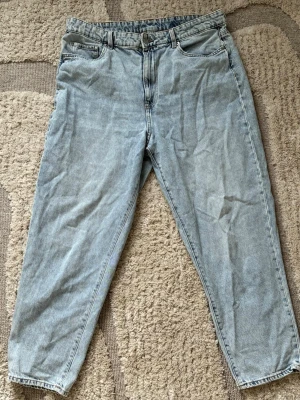 Ljusblå loose fit jeans från H&M - Säljer ett par ljusblå loose fit jeans från H&M med klassisk femficksmodell och dragkedjegylf. Jeansen har en avslappnad passform och är tillverkade i 100% bomullsdenim. Perfekta för en chill och trendig look. Passar L/XL