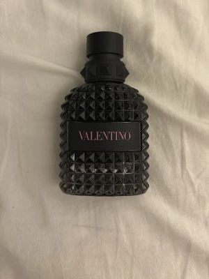 Valentino parfym intense 50ML - Snygg parfym från Valentino i en svart, robust glasflaska med nitar och mönstrad yta. Flaskan har en modern och edgy design med Valentino-loggan i rosa på svart etikett. Perfekt för dig som gillar exklusiva dofter och coola detaljer. Knappt 1cm av parfymen har använts. Vid ytligare frågor eller funderingar kan ni skicka privat för närmare bilder osv! Box finns med och denna parfym är äkta! Är köpt från Åhléns