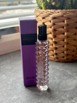 Valentino Donna Born In Roma EdP - Lyxig parfym från Valentino i en transparent, mönstrad glasflaska med svart spraykork. Kommer i en snygg lila kartong med svart detalj. Doften är en Eau de Parfum och flaskan har en cool, modern design med nitar.