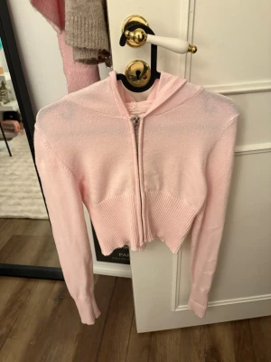 Ljusrosa cropped hoodie Gina Tricot - Supersöt ljusrosa cropped hoodie från Gina Tricot med dragkedja framtill och ribbade detaljer vid midja och ärmslut. Tillverkad i mjukt stickat material och har en klassisk huva. Perfekt för en chill och trendig look. Använd 1 gång tidigare men är i som nytt skick💗