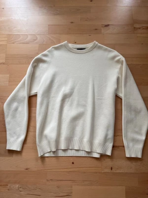 Klassisk cremevit stickad tröja från ZARA - En stilren cremevit stickad tröja med rund hals och ribbade muddar vid ärmslut och nederkant. Tröjan har en enkel och clean design som passar till det mesta. Perfekt för lager på lager och enkel att matcha med olika outfits.