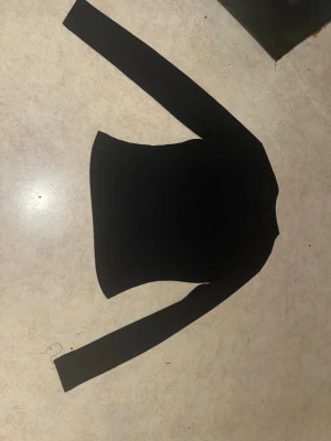 Svart långärmad topp - En enkel och stilren svart långärmad topp med rund hals. Toppen har en tight passform och är tillverkad i ett mjukt, stretchigt material som sitter snyggt på kroppen. Perfekt att matcha med jeans eller kjol för en clean look.
