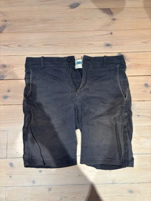 Svarta shorts från WinWin - Snygga svarta shorts från Guess med klassisk passform och bälteshällor. Shortsen har dragkedja fram, två sidofickor och två bakfickor. Tillverkade i mjuk bomull som passar perfekt till sommaren.