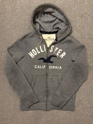 Vintage Hollister Zip-Hoodie - Säljer denna riktigt snygga Hollister zip hoodien | Storlek S | Mycket bra skick | Längd ≈66cm , Bredd armhåla-armhåla ≈52 | Model 175cm, 68kg | Hör av vid funderingar! 