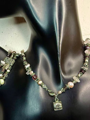 Baglady 90-tal 00-tal Matchande Vintage Smyckeset – Äkta Ädelstenar Rosenkvarts, Granat & Sötvattenspärlor Orient Boho - Vackert 90-tal/00-tals vintage smyckeset från Baglady med halsband och matchande armband. Smycket består av rosenkvarts, granat, bergkristall och sötvattenspärlor tillsammans med dekorativa metalldelar i silvrig metall. Designen har tydlig orientaliskt inspirerad boho-stil med rika färger och dekorativa detaljer.  Mått: halsband ca 44 cm, hänge ca 7,5 cm. Armband ca 18 cm ostretchat (elastiskt), ca 2 cm brett.  Fint bruksskick. Jag prutar inte, men erbjuder bra rabatt vid köp av flera saker.