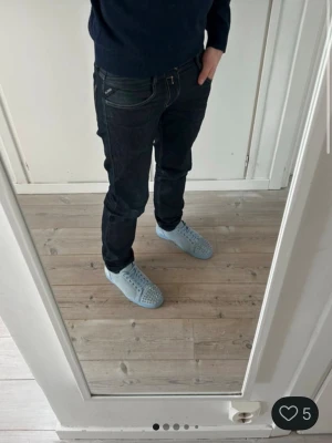 Mörkblå Replay jeans med slitningar - Säljer ett par mörkblå jeans från Replay med snygga slitningar och tvättade detaljer. Klassisk femficksmodell med smal passform och kontrastsömmar. Märkeslogga på fickan och bakfickan har en cool reva för extra edge. Perfekta för dig som gillar streetstyle.