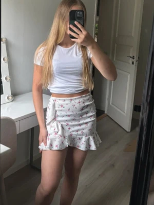 Kort blommig kjol med volang  - Kan ha varit använd ett tillfälle, om inte helt oanvänd. Nyskick, lite liten i storlek mer som en xs än en S.