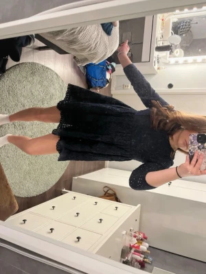 Mörkblå kort klänning med spetsdetaljer - Söt mörkblå kort klänning med långa ärmar och fina spetsdetaljer över hela tyget. Klänningen har en rund halsringning och lätt utställd kjol som ger en feminin siluett. Perfekt för dig som gillar en klassisk men ändå trendig look. Köpte från Sellpy men är originellt från Zara.