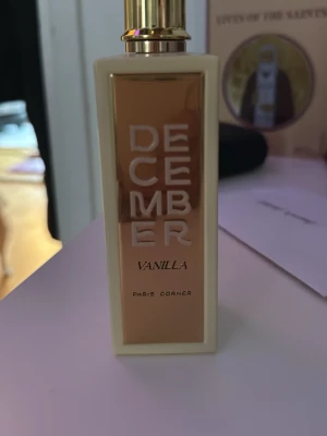 December Vanilla parfym Paris Corner - Endast använd 4-5 gånger. December Vanilla från Paris Corner är en lyxig parfym i en rektangulär, krämvit flaska med guldfärgade detaljer och lock. Flaskan har en elegant vaniljblomma ingraverad på baksidan och text i vitt och svart. Doften har inslag av vanilj, brunt socker och oud.