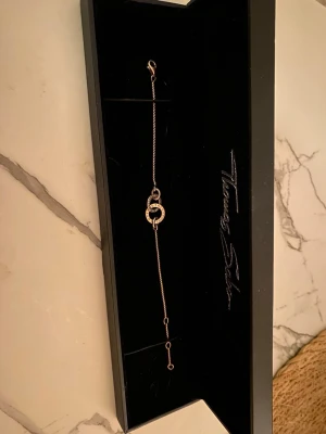 Thomas Sabo armband - Snyggt armband från Thomas Sabo i roséguld med två sammankopplade cirklar i mitten. Ena cirkeln är dekorerad med små gnistrande stenar som ger en exklusiv känsla. Tunt och elegant kedjearmband som passar perfekt till din vardagsstil. Rose färgat silver som tappat lite färg därefter priset. Syns bara om man tittar noggrant 