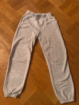 Grå mjukisbyxor med resår - Säljer ett par klassiska grå mjukisbyxor med resår i midjan och vid bensluten. Byxorna har en avslappnad passform och är tillverkade i mjukt bomullsmaterial, perfekta för chill dagar hemma eller när du vill vara bekväm.