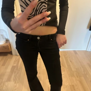 Svarta utsvängda jeans med låg midja - Säljer ett par svarta jeans med låg midja i bra skick.