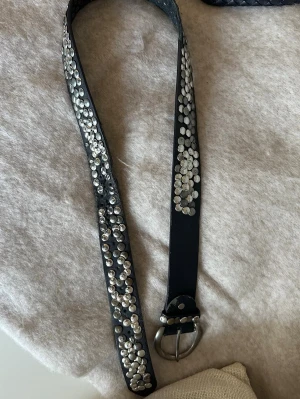 Svart bälte med silvernitar - Snyggt svart bälte dekorerat med massor av silverfärgade nitar längs hela bandet. Från Tessie. Använt, därmed finns slitage på skärpet som syns på bilderna🩶💙🩷