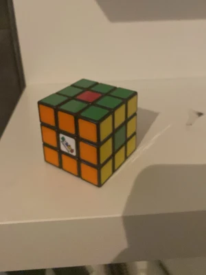 Rubiks kub 3x3 klassisk färgglad - Rubiks kub 3x3 med klassiska färger: grön, orange, gul, vit och röd. Kuben har svart ram och färgade klistermärken på varje sida. Perfekt för dig som gillar kluriga pussel och vill utmana hjärnan.
