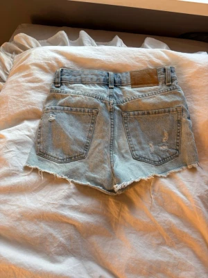 Ljusa denimshorts med slitningar - Säljer ett par ljusblå denimshorts i storlek XXS. 