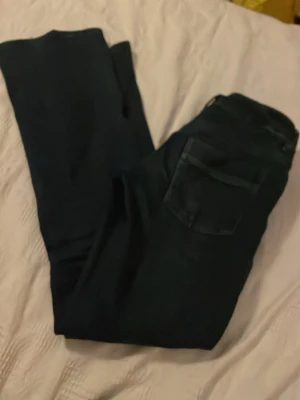 Mörkblå jeans med klassisk passform lågmidjade - Snygga mörkblå jeans i klassisk modell med fem fickor och boot cut  ben. Jeansen har en enkel design utan synliga loggor och är tillverkade i denim. Perfekta för en stilren och avslappnad look.De är ganska lågmidjade.