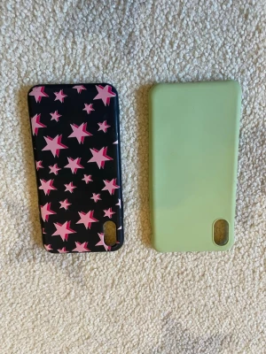Två mobilskal, stjärnor & mintgrön IPhone XS - Säljer två mobilskal: ett svart skal med rosa stjärnor i olika storlekar och ett enfärgat mintgrönt skal. Båda har öppning för kamera och är tillverkade i plast. Perfekt för dig som vill variera stilen på din mobil!