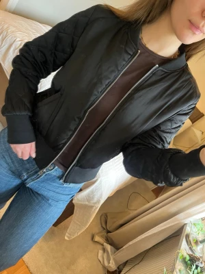 Svart bomberjacka- storlek S - Svart vårjacka med rutiga detaljer på ärmarna, två fickor - H&M  Storlek S (står 42 men sitter som S)