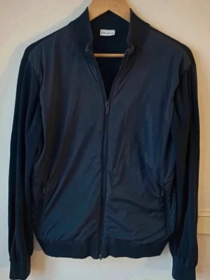 John Henric cardigan strl M - Säljer en John Henric cardigan i storlek M. Den är mörkblå och i bra skick förutom att den tappat den nedre dragkedja dragen. Perfekt inför kommande vår och sommar. Styla med en tröja, skjorta eller t-shirt under. Hör av er vid frågor och funderingar!