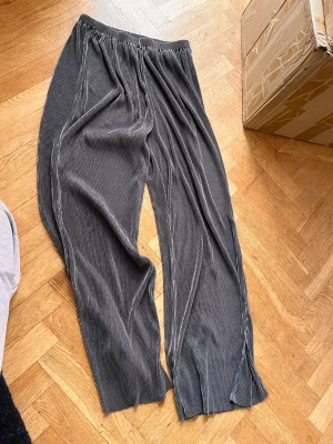 Grå ribbade mjukisbyxor med slits - Säljer ett par grå mjukisbyxor med ribbad struktur och vida ben. Byxorna har elastisk midja och slitsar nertill vid bensluten för en avslappnad och trendig look. Perfekta för chill dagar hemma eller när du vill vara bekväm men ändå se snygg ut.Skriv gärna för mått! 💕