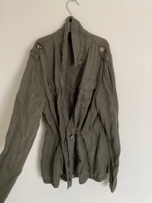 Tunn grön jacka  - Säljer denna tunna gröna jacka, den stängs med knappar och har ett snöre på insidan som man kan spänna åt den i midjan med, perfekt nu till våren 💗