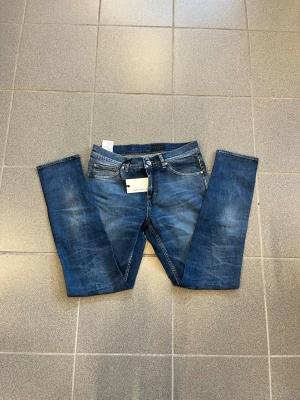 Blå slim fit jeans från Tiger of sweden W29 L32 - Snygga blå slim fit jeans från tiger of sweden med klassisk femficksdesign och lätt slitna detaljer. Jeansen har normal midja, dragkedjegylf och är tillverkade i stretchig denim för extra komfort. Perfekta till en avslappnad stil.
