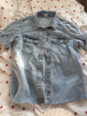 Ljusblå kortärmad jeansjacka - Säljer en ljusblå kortärmad jeansjacka med två bröstfickor med knappar och rå kant nertill ifrån BikBok. Jätte fint att style  inför sommaren❤️