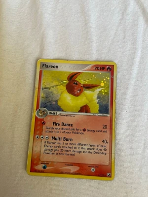 Flareon Pokémonkort holografiskt - Säljer ett holografiskt Flareon-kort från Pokémon TCG. Kortet har en färgstark design med gul, röd och orange bakgrund och Flareon i fokus. Text och effekter på engelska. Perfekt för samlare eller Pokémonfans!