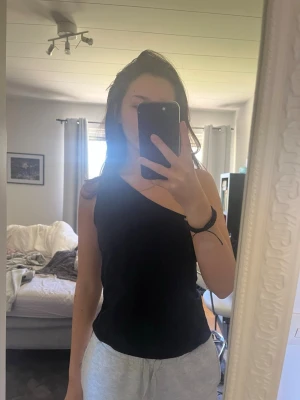 Svart oneshoulder topp - Svart oneshoulder topp med enkel och stilren design.