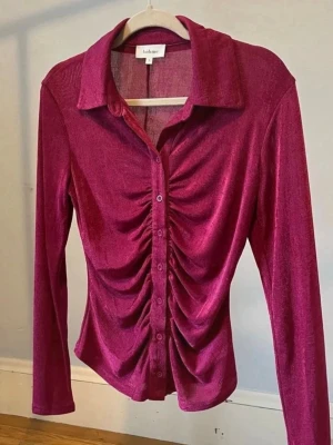 Rosa skjorta - Snygg rosa skjorta . Skjortan har långa ärmar, klassisk krage och knappar framtill. Framsidan är rynkad för en cool och trendig look. Perfekt för dig som vill sticka ut med din stil.