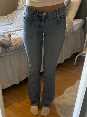 Blå raka jeans med mellan hög midja - Säljer ett par klassiska blå jeans med rak passform och hög midja. Jeansen har fem fickor och stängs med knapp och dragkedja. Perfekta till en avslappnad stil och passar till det mesta. Materialet är denim i bomull.