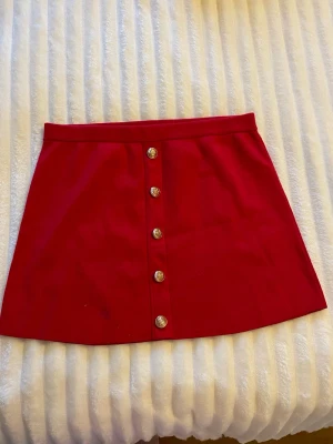 Röd kortkjol med knappar framtill - Snygg röd kortkjol med knappar längs framsidan. Materialet är mjukt och den är väldigt bekväm❤️