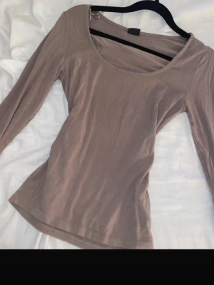 Beige långärmad topp Gina Tricot - En enkel och stilren beige långärmad topp från Gina Tricot. Toppen har rund halsringning och är gjord i mjukt material som sitter snyggt mot kroppen. Perfekt att matcha med jeans eller kjol för en clean look.