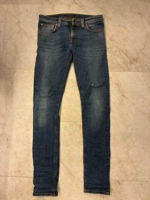 Nudie jeans - Mörkblå nudie jeans i mycket bra skick. Jeansen har inga defekter och är knappt använda. Dem är i storlek 28/32. Dem har en liten slitning och är väldigt stilrena, funkar till det mesta. Hör av er vid frågor!
