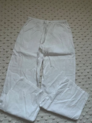 Vita linnebyxor från Gina Tricot - Säljer ett par vita linnebyxor från Gina Tricot med avslappnad passform och resår i midjan. Byxorna är tillverkade i ett lätt och luftigt linnematerial, perfekta för varma dagar. Klassisk rak modell som är enkel att matcha med olika toppar.