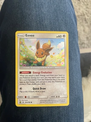 Pokémonkort Eevee Sun & Moon - Säljer ett Pokémonkort med Eevee från Sun & Moon-serien. Kortet har gul ram, färgglad illustration och text på engelska. Perfekt för samlare eller Pokémonfans som vill utöka sin kortsamling.