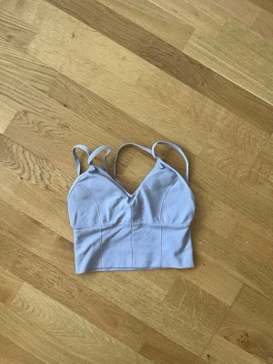 Ljuslila crop bralette med smala band - Snygg ljuslila bralette med smala axelband och v-ringning. Modellen är croppad och har sömdetaljer framtill för en stilren look. Mjukt och stretchigt material, perfekt för en bekväm känsla hela dagen.
