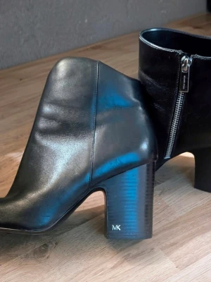 Svarta stövletter från Michael Kors - Snygga svarta stövletter i skinn från Michael Kors med grov klack och silverfärgad dragkedja på sidan. Klassisk design med rundad tå och diskret MK-logga på klacken. Perfekta för dig som vill ha en stilren och trendig look. Endast provade en kväll men va inget för mig. 
