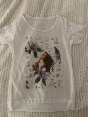 T shirt - En vit t shirt med spetsdetaljer på ärmarna och ett tryck.  (Den är ganska så genomskinlig), storlek S . Inte använts. 🩷