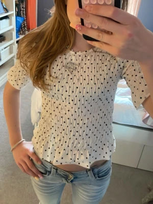 Vit prickig blus från Gina Tricot - Supersöt vit blus med svarta prickar från Gina Tricot. Blusen har smock över hela kroppen och korta ärmar. Perfekt till jeans eller kjol för en trendig look. Materialet känns mjukt och följsamt.