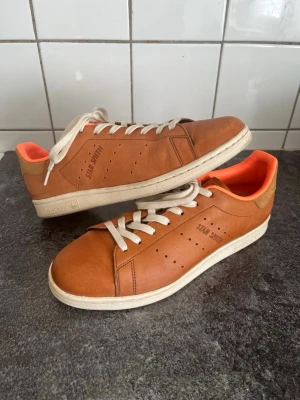Adidas Stan Smith Horween Tannery - Adidas Stan Smith Horween Tannery. Limiterad modell i brunt läder med vita snören och sula. Insidan är fodrad i en stark orange färg som ger en cool kontrast. Klassisk låg modell med perforerade detaljer på sidorna och Stan Smith-logga. Perfekta för dig som vill sticka ut med din stil. Sälj för upp emot $300 på den internationella marknaden. 