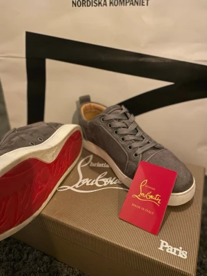  Christian Louboutin  - Säljer ett par Christian Louboutin sneakers i grå mocka. Klassisk och stilren modell med den ikoniska röda sulan som verkligen sticker ut. Skriv om ni har frågor och priset är inte bankat i sten.