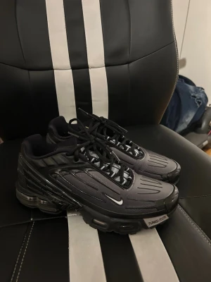 Nike Tuned Air sneakers - Snygga svarta Nike Tuned Air sneakers med futuristisk design och reflekterande detaljer. Skorna har snörning och en robust sula med synlig dämpning. Perfekta för dig som gillar streetwear och vill ha något som sticker ut.