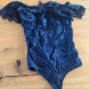 Marinblå off shoulder body - Body i spets med snygg off shoulder i volang. Aldrig använt! Perfekt för lite mer uppklädda tillfällen