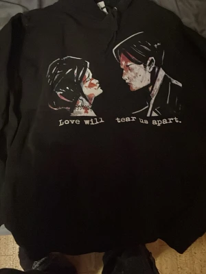 Svart My Chemical Romance hoodie - Cool svart hoodie med tryck av två ansikten och texten 'Love will tear us apart' på framsidan. På ryggen står det 'My Chemical Romance' i vit text. Hoodien har huva och är perfekt för dig som gillar bandmerch och alternativ stil.
