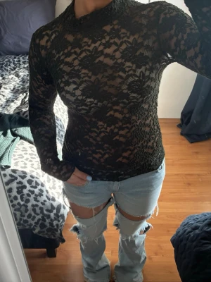 Svart spetsblus från InWear - Säljer en svart långärmad blus från InWear i storlek S. Blusen är helt i spets med ett blommigt mönster och har en hög hals. Perfekt för dig som gillar detaljer och vill ha en elegant look med transparent känsla.